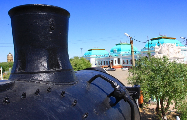 Паровозная труба на фоне железнодорожного вокзала в Казалинске.