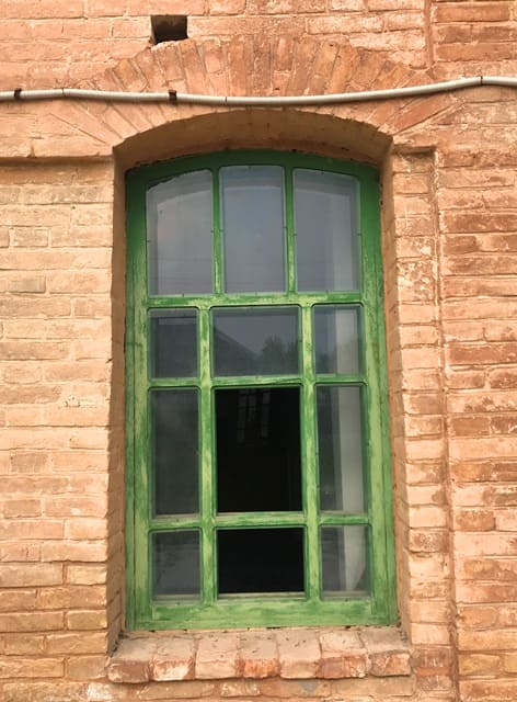 Nogai Ishan Mosque. An antique wooden window is distinguished by its arched upper part and bright green paint. The window is installed in a red brick opening, typical of historic buildings. 2024