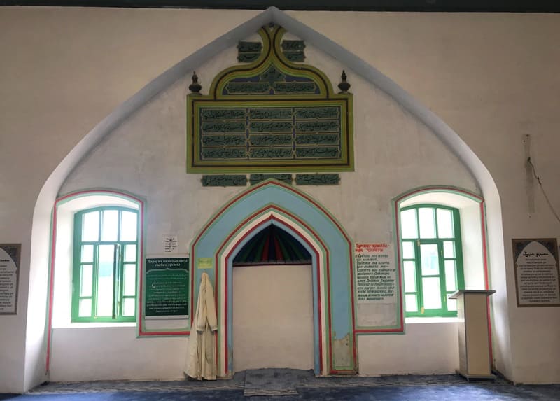 Mihrab - a niche in the wall indicating the direction of Mecca (qibla). The walls are decorated with traditional elements and information boards with Arabic calligraphy. Nogai Ishan Mosque. 2024