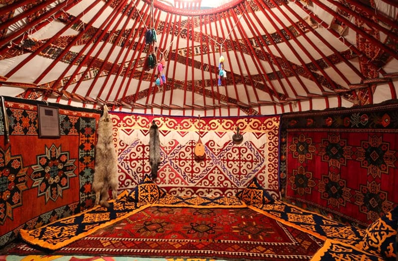 Interior of a traditional Kazakh yurt (kiіz үй). The yurt, an ancient portable nomadic dwelling, is distinguished by its practicality, ease of assembly, and transportation. The structure consists of a wooden frame covered with felt, providing protection from various weather conditions. The interior is decorated with traditional carpets (syrmak, tuskiiz) with traditional patterns reflecting the cultural heritage. The yurt is an important symbol of Kazakhstan's culture, embodying the philosophy of the unity of man and nature.