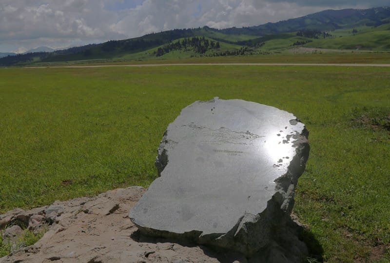 A memorial marker commemorating the visit of Chokan Valikhanov to the area of the San-Tash burial mound. The stone bears an engraved image of a mountain landscape and an inscription related to Valikhanov’s 1856 expedition. 2002.