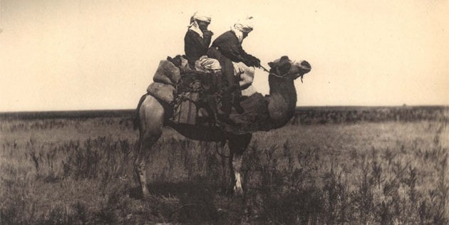 Две киргизки на верблюде в плоской степи.