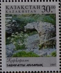 Stamp depicts a snow leopard (irbis) in a natural landscape. This is a Kazakhstan postage stamp issued in 1997.